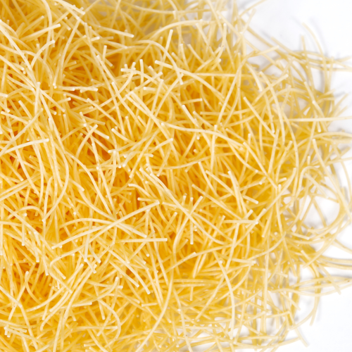 Nahaufnahme von rohen Fadennudeln, ungekocht und locker gestapelt auf weißem Hintergrund.